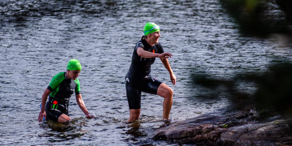 Två swimrunners går upp ur vattnet i Skatås sjöar